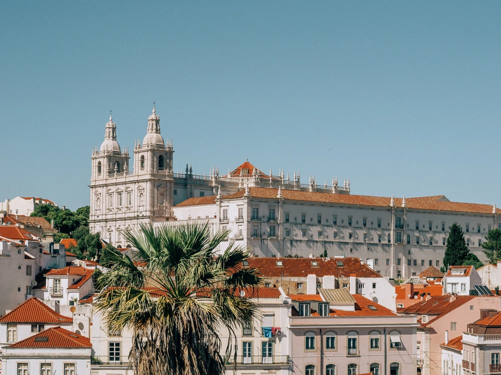 A scenic view of the historic São Vicente de Fora Monastery overlooking the charming terracotta rooftops of the Alfama district in Lisbon.