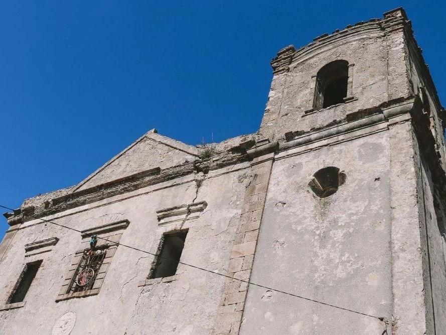 The historic stone ruins of the Convento de Nossa Senhora do Desterro in Monchique against a clear blue sky.