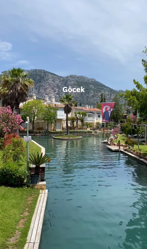 A peaceful canal in the upscale sailing town of Göcek, Turkey, lined with waterfront villas and lush palm trees.