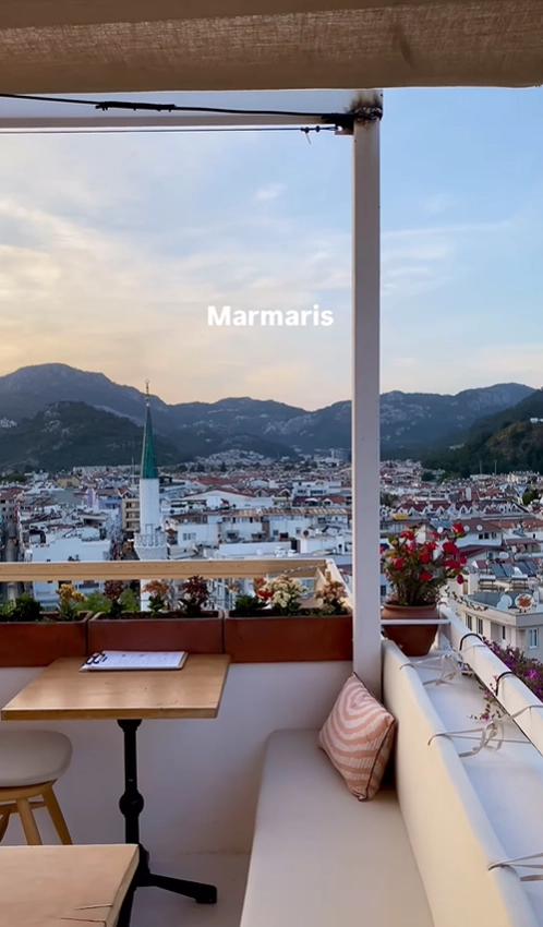 An expansive evening view from a balcony overlooking the Marmaris bay, town, and surrounding mountains along the Turkish coast.