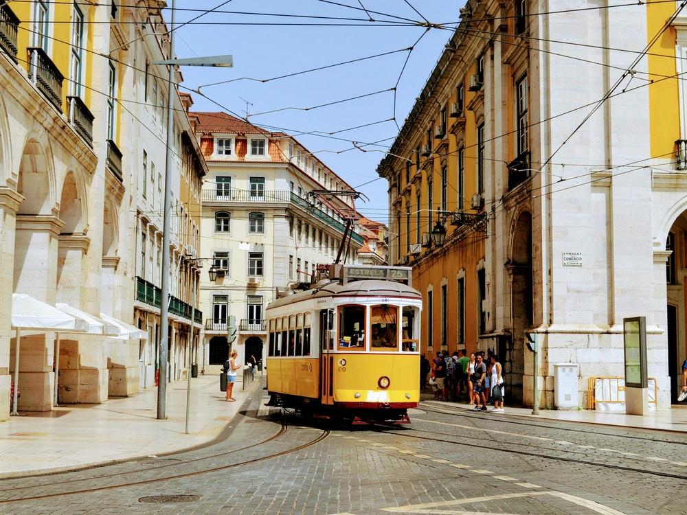 A classic yellow tram, a famous symbol of the city, making its way through the charming, narrow cobblestone streets of Lisbon.