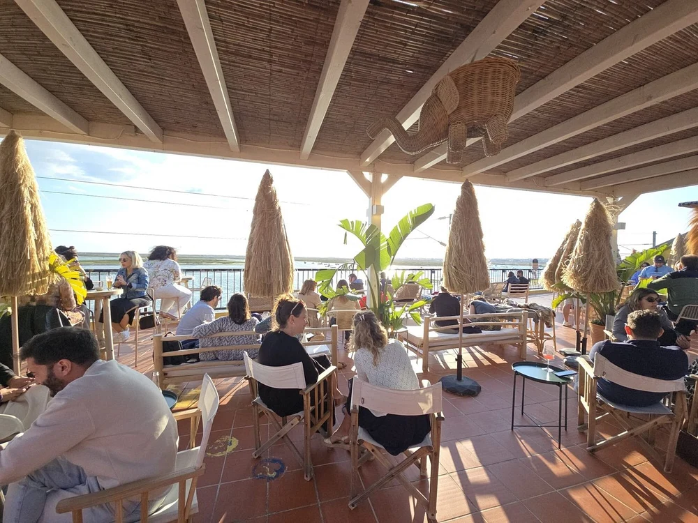 People relaxing and enjoying the golden hour ambiance at the trendy Lab Terrace sunset bar overlooking the Ria Formosa.