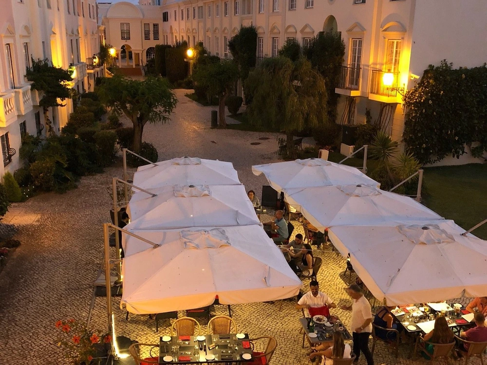An atmospheric evening at the Old Village in Vilamoura, showing diners in a charming cobblestone courtyard surrounded by traditional architecture.