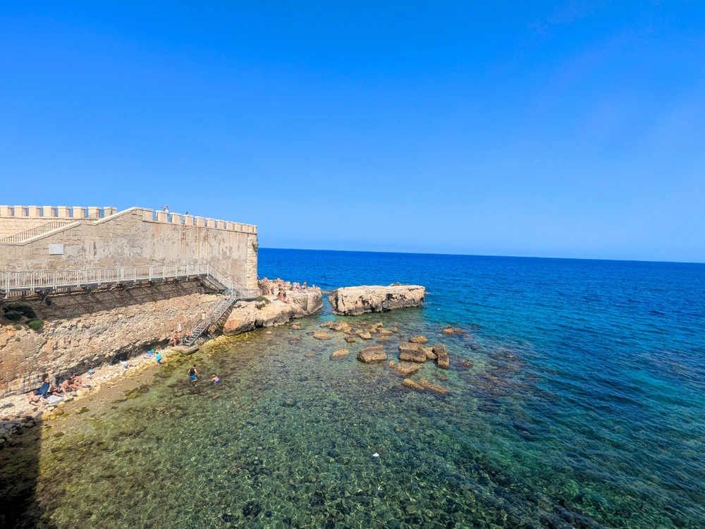 Locals swimming at Forte Vigliena’s rocky seaside platform on Ortigia’s southern coast