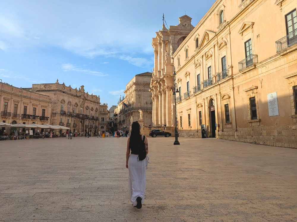 Woman walking through the open square of Piazza Duomo with the cathedral in view