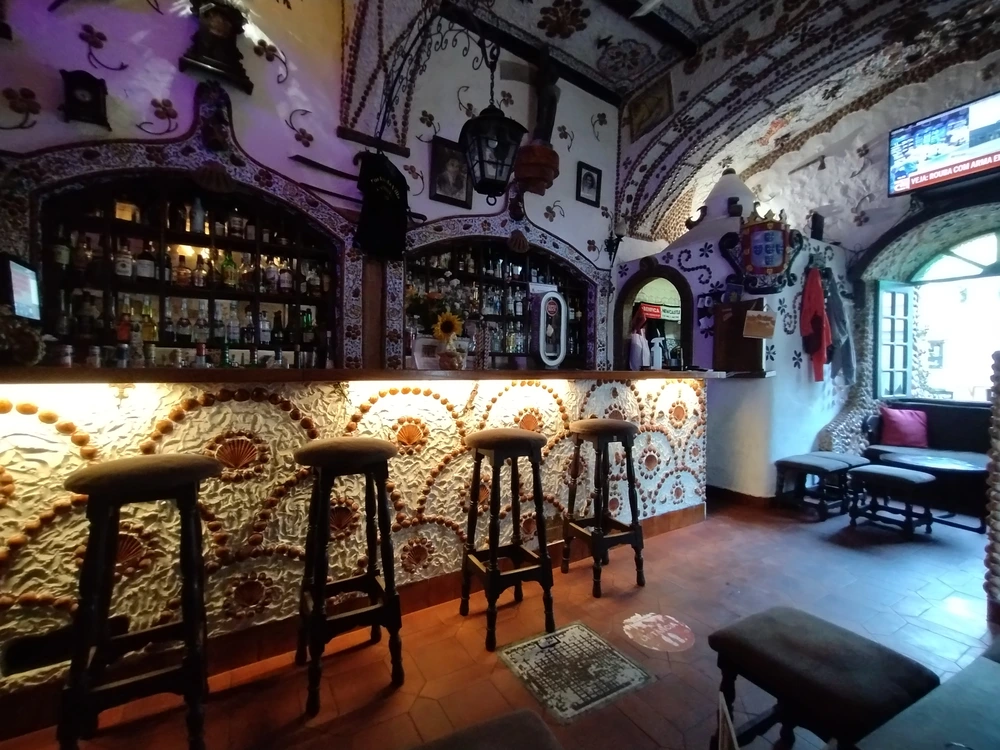 The unique and historic interior of Portas da Villa antiquity bar in Albufeira, with its famous bar and arched ceilings intricately decorated with seashells.