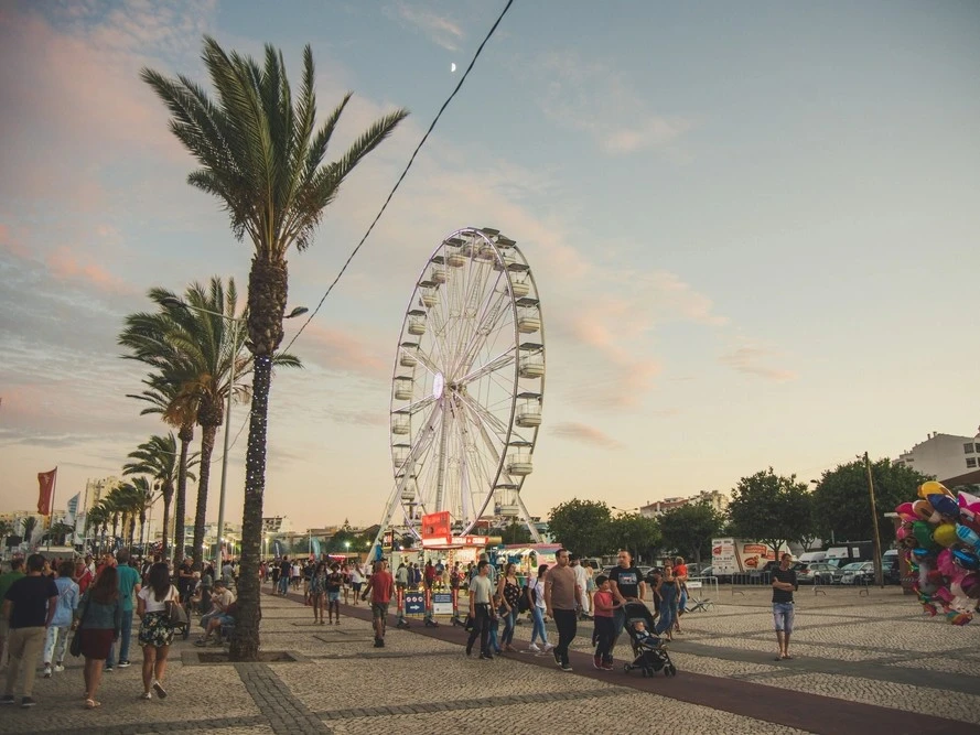 Ferris wheel and food stalls along the Portimão waterfront during a summer festival evening