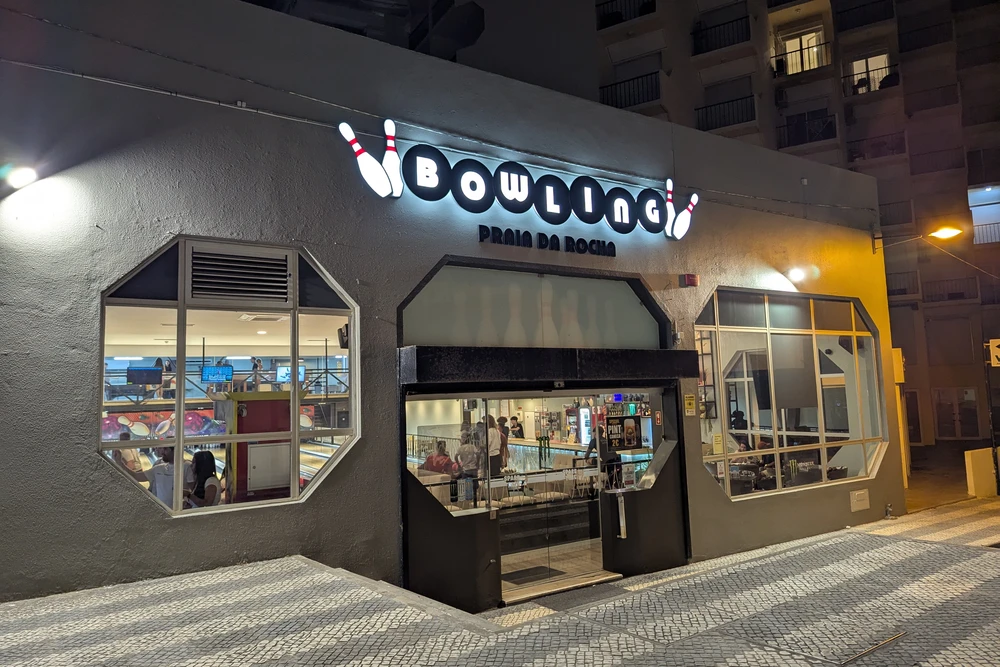 Bowling alley in Praia da Rocha lit up at night with people inside enjoying games