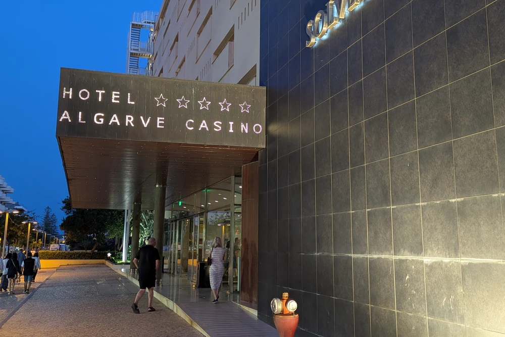 Entrance to Hotel Algarve Casino in Praia da Rocha with illuminated sign and evening visitors