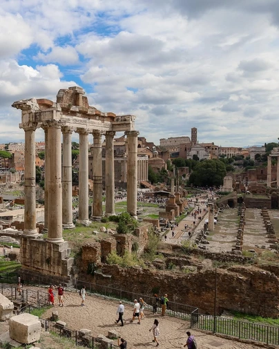 The majestic ruins of the Roman Forum, with the columns of the Temple of Saturn in the foreground. This unique perspective highlights finding non-touristy viewpoints of famous historical sites in Rome.
