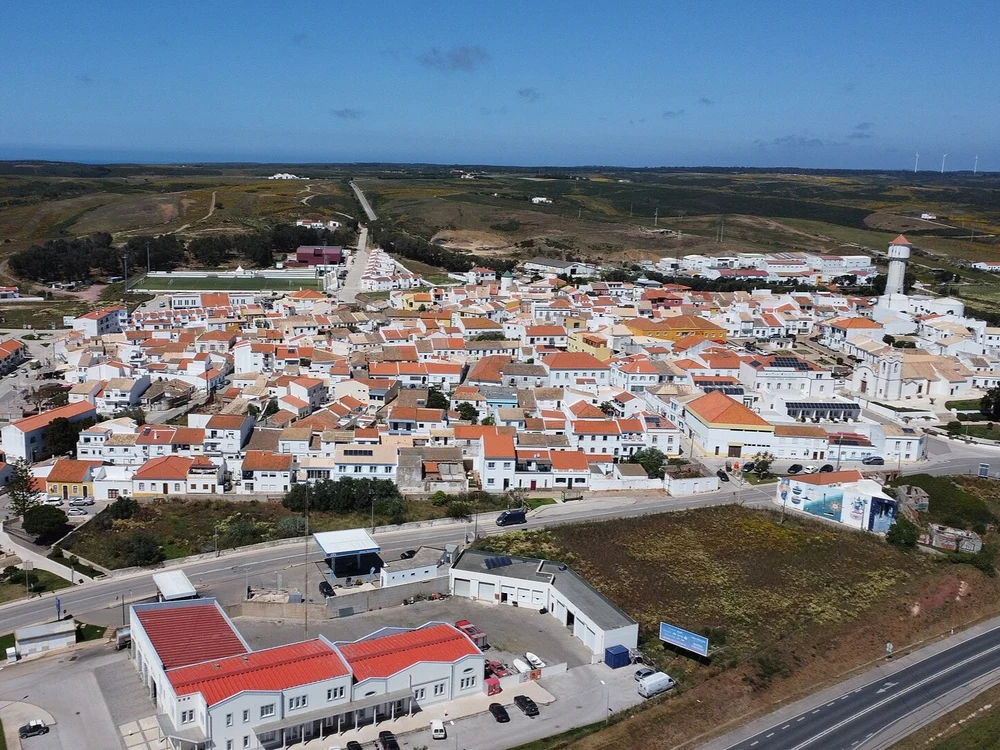 An expansive aerial view overlooking the charming town of Vila do Bispo, showing its traditional white buildings and terracotta roofs.