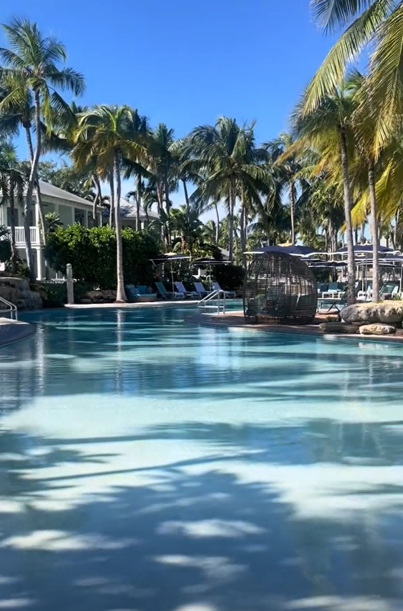 The serene, palm-tree-lined swimming pool at Sunset Key Cottages resort in Key West.