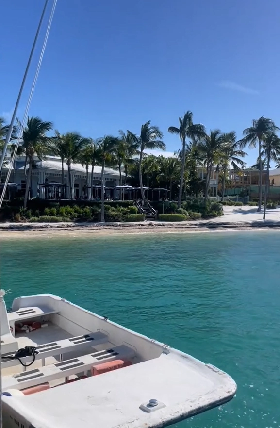 View from the ferry boat arriving at the shore of Sunset Key, showing the island's beach and palm trees from the water.