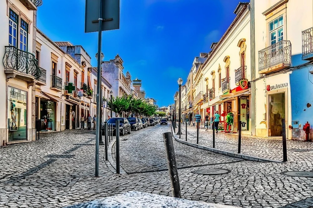 Wide, cobblestone street of Rua da Liberdade, the main shopping and commerce area in the heart of Tavira, Portugal.