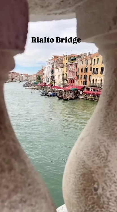 A scenic view of Venice's Grand Canal as seen through an arch of the iconic Rialto Bridge, a classic city viewpoint.