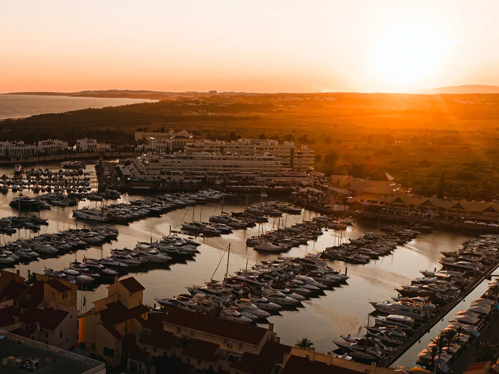 Golden sunset over the Vilamoura Marina, with an aerial view of hundreds of yachts docked in the harbor in Vilamoura, Portugal.
